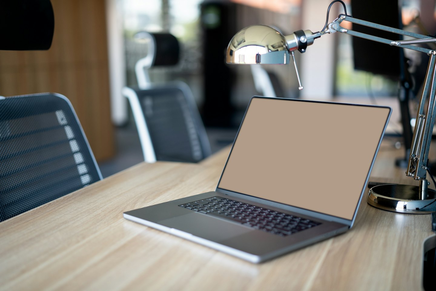Nowoczesny laptop stoi na jasnym drewnianym biurku.