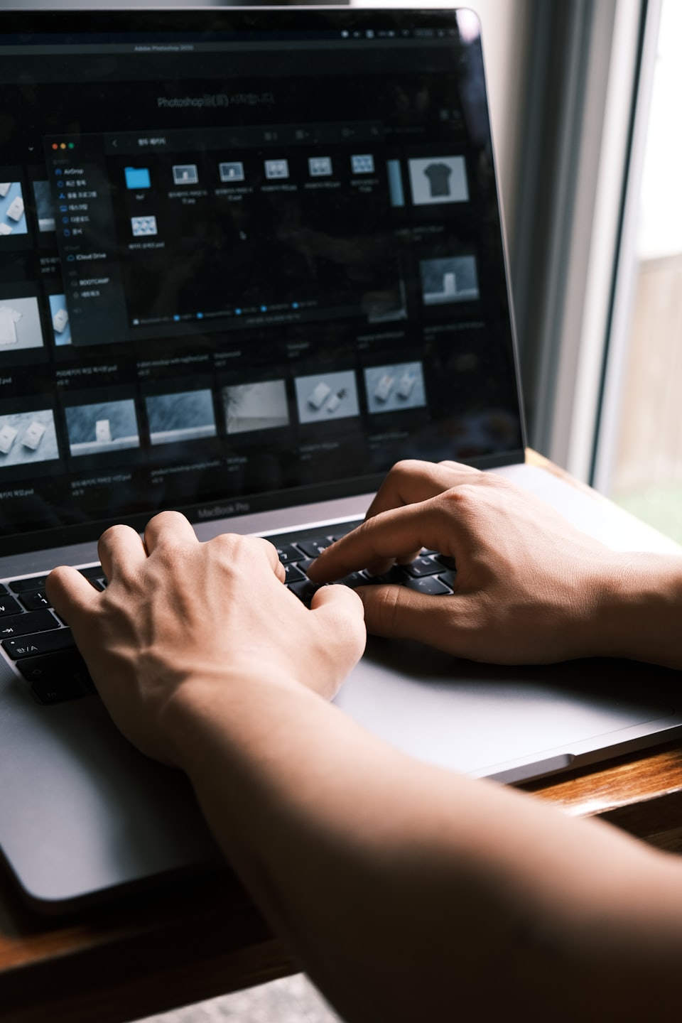 Dłonie piszące na laptopie z makietami projektowymi na ekranie.